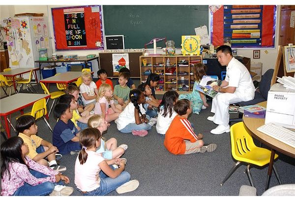 1 Mess Management Specialist Gui Gagui, Armed Forces Committee Chairperson, reads a book to a group of 1st grade students at E J King Elementary School