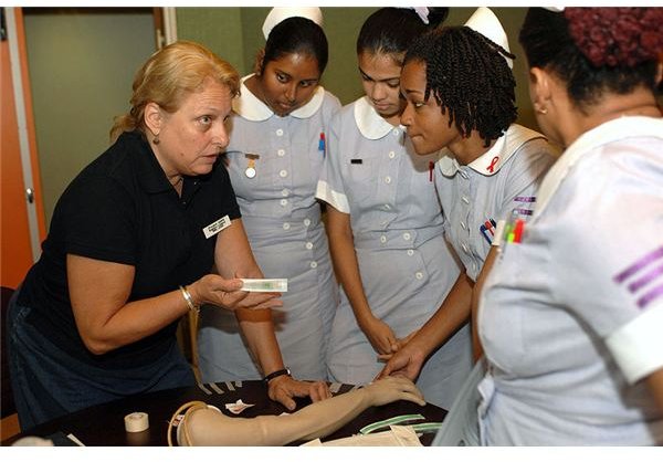 Genie Lindsey, a registered nurse with Project Hope attached to Military Sealift Command hospital ship USNS Comfort explains the correct procedures for administering an intravenous tube to 