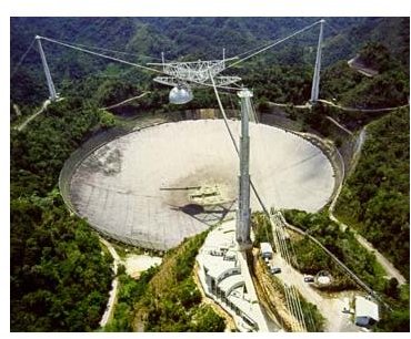 The enormous dish of the Arecibo Observatory. The reflector is suspended 450 feet above the dish and weighs roughly 900 tons; suspending this platform are large cables strung from the reinforced concrete pillars, one 365 feet tall, the other two 265 feet tall. 