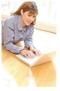 Woman typing on laptop computer on hardwood floor uid 1279412