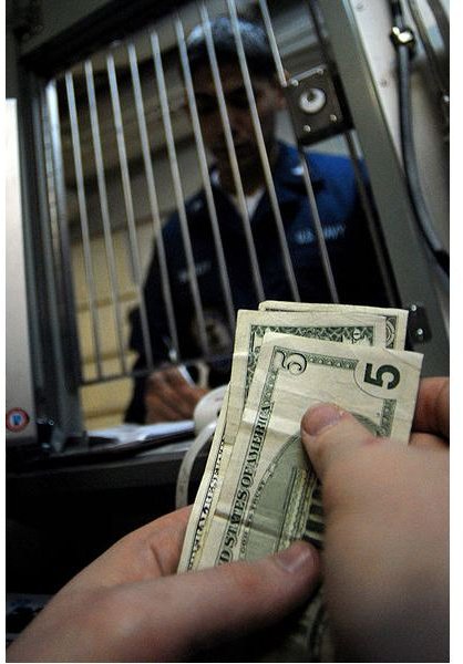 Personnel Specialist Seaman Chris Rasco receives money from Electronics Technician 3rd Class Adam Stevenson to put on his Navy cash card while visiting the disbursing office aboard Nimitz-class 