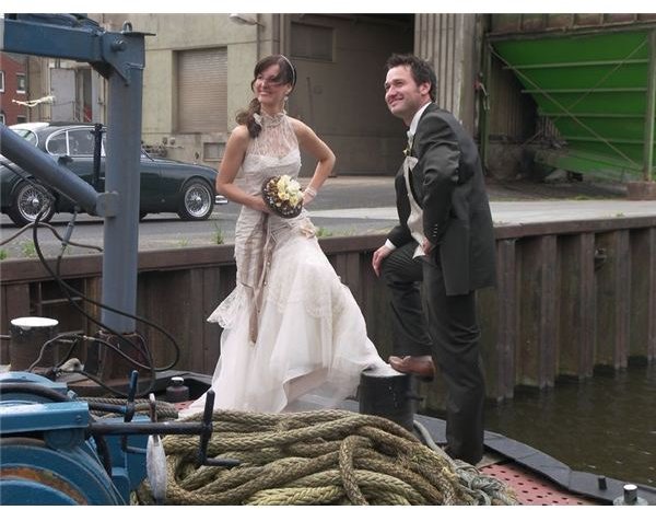 Newly-wed couple stand on the bow of a boat.